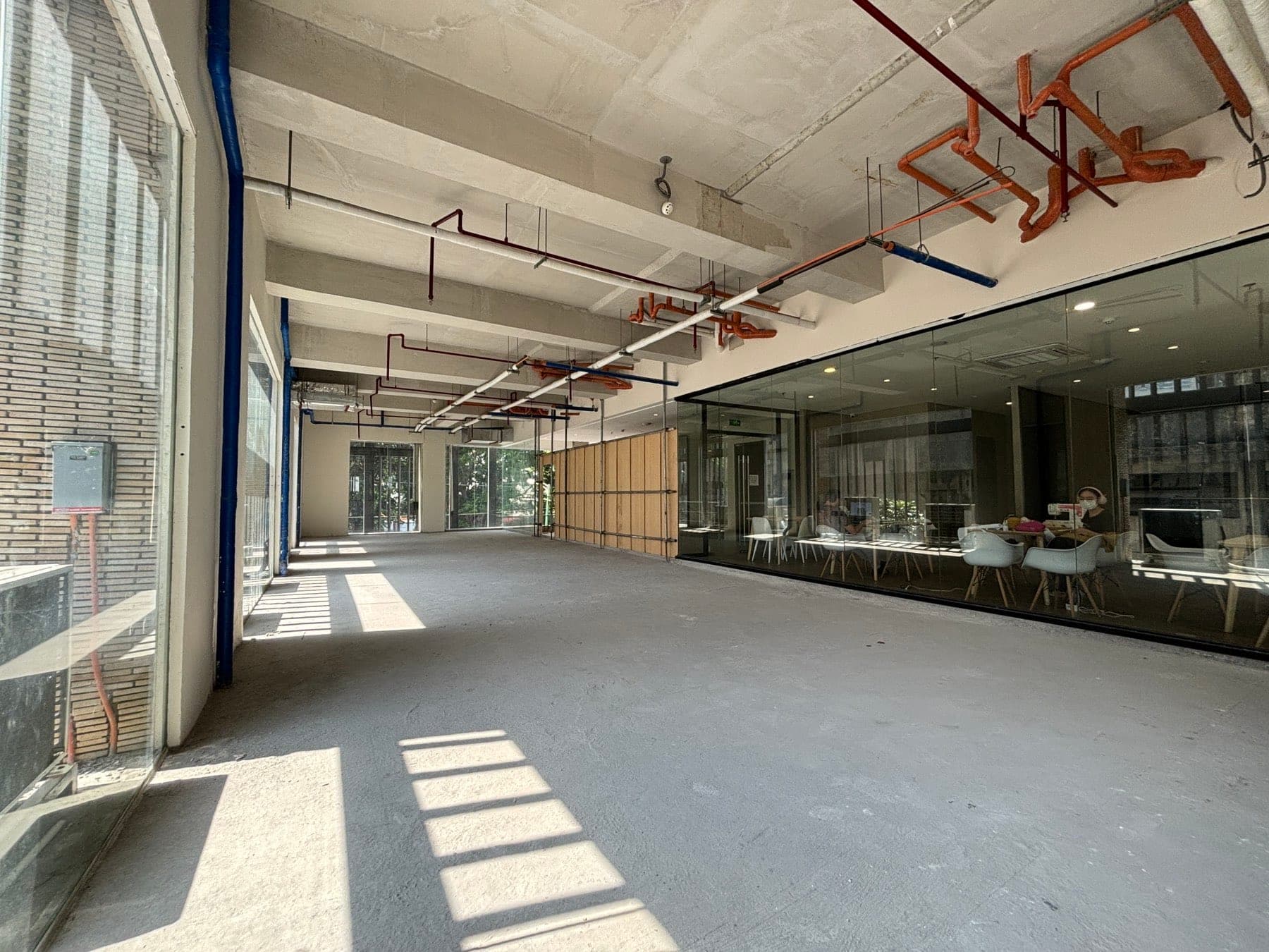Long view of the bare shell with exposed sprinkler and services above, glazing along the left wall