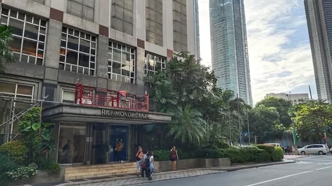 Richmonde Plaza from the street in Ortigas Center, entrance canopy and signage below the tower, with palms along the frontage